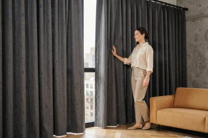 Femme admirant des rideaux occultants gris anthracite en lin dans un salon moderne avec parquet en chêne